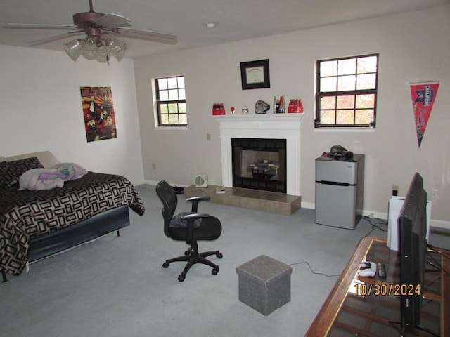 carpeted bedroom featuring white fridge, ceiling fan, and a tiled fireplace