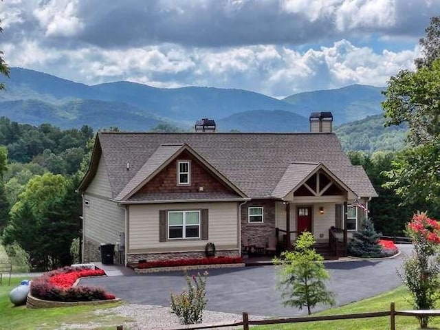 craftsman-style home with driveway, a chimney, a front yard, and a mountain view