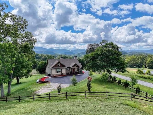 exterior space featuring a fenced front yard, a yard, a mountain view, a rural view, and driveway