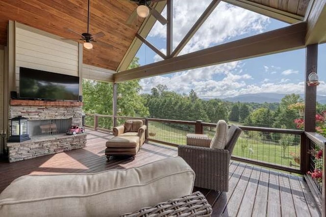 deck with an outdoor living space with a fireplace and a ceiling fan