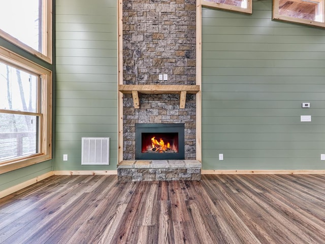 unfurnished living room with a fireplace, wood walls, and hardwood / wood-style floors