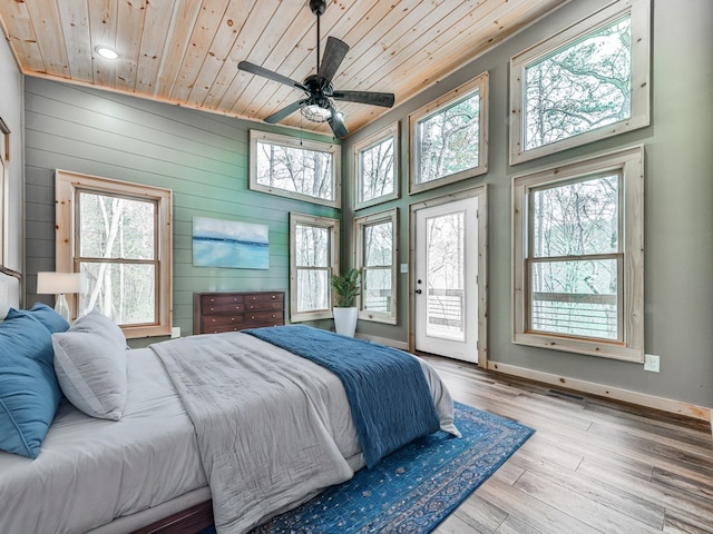 bedroom with access to exterior, light hardwood / wood-style floors, multiple windows, and wooden ceiling