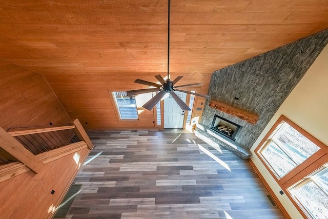 unfurnished living room featuring lofted ceiling, a stone fireplace, a healthy amount of sunlight, and wood ceiling