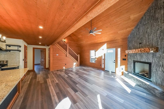 unfurnished living room featuring dark wood-type flooring, a stone fireplace, wood walls, lofted ceiling, and wood ceiling