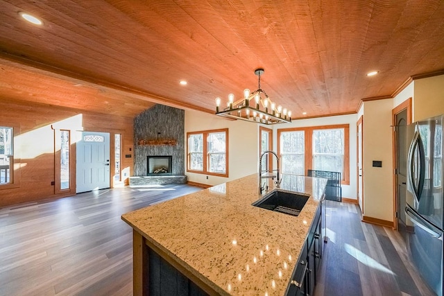 kitchen with stainless steel fridge, a center island with sink, pendant lighting, and dark hardwood / wood-style floors