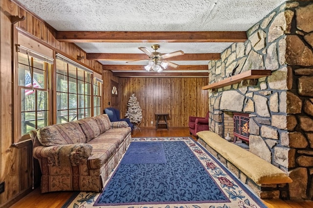 living room with a textured ceiling, ceiling fan, wood walls, and hardwood / wood-style flooring