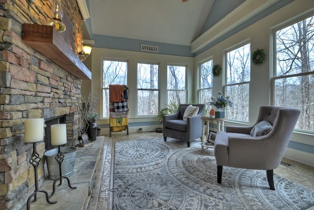 living area featuring lofted ceiling, a stone fireplace, and a wealth of natural light