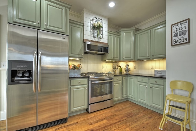 kitchen featuring decorative backsplash, light hardwood / wood-style flooring, stainless steel appliances, and green cabinetry