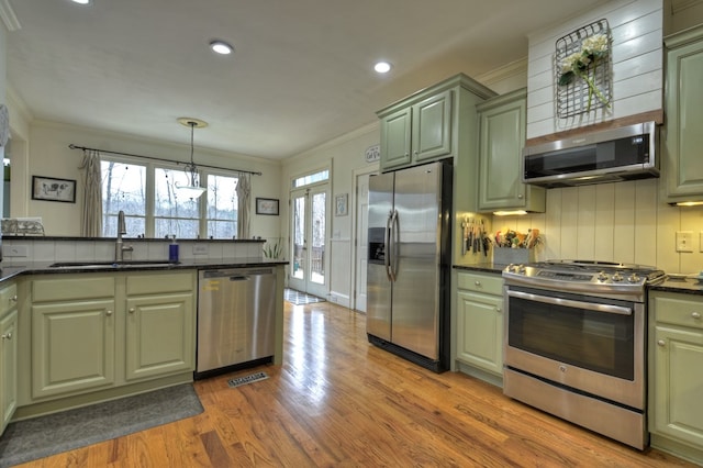 kitchen with sink, tasteful backsplash, green cabinets, pendant lighting, and stainless steel appliances