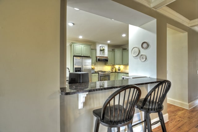 kitchen featuring backsplash, a breakfast bar area, stainless steel appliances, and kitchen peninsula