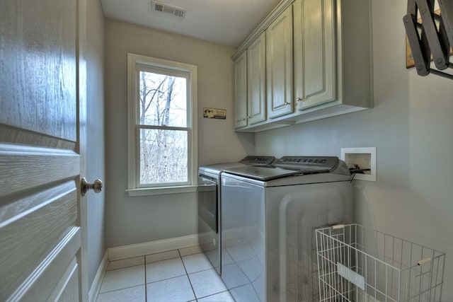 laundry area with washer and dryer, light tile patterned floors, and cabinets