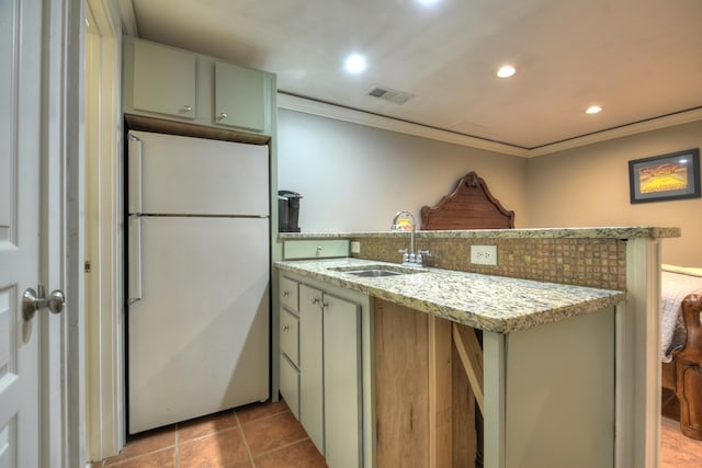 kitchen with white refrigerator, light stone countertops, sink, and kitchen peninsula