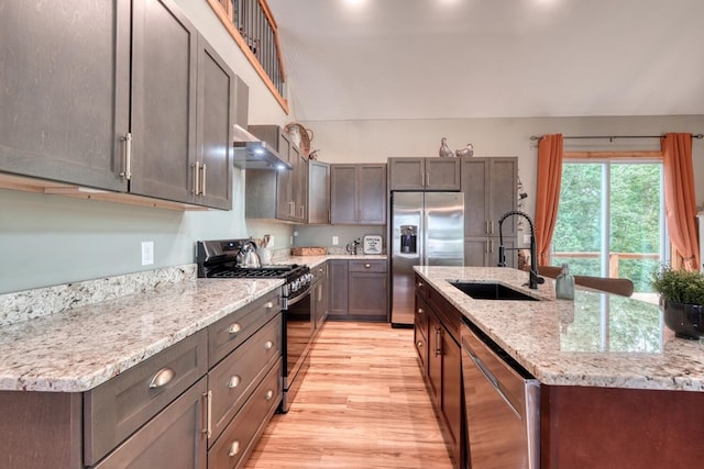 784 Sneaking Creek Dr, Hayesville, NC 28904 - kitchen with stainless steel appliances, light wood-type flooring, light stone counters, an island with sink, and wall chimney range hood