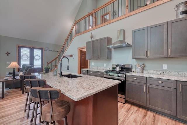 784 Sneaking Creek Dr, Hayesville, NC 28904 - kitchen with wall chimney exhaust hood, stainless steel gas stove, high vaulted ceiling, light wood finished floors, and light stone counters