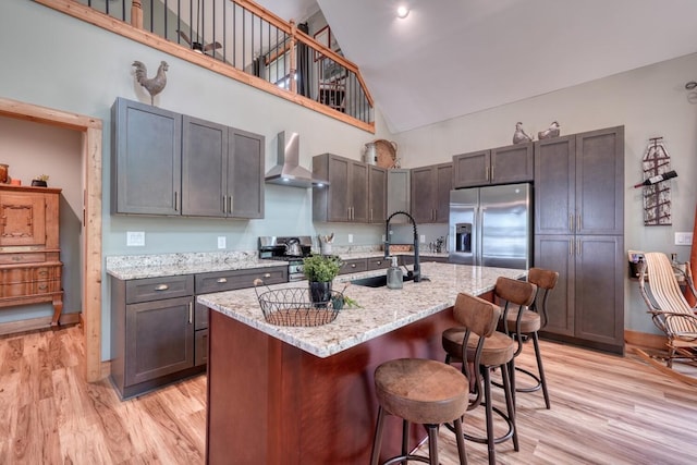 784 Sneaking Creek Dr, Hayesville, NC 28904 - kitchen featuring appliances with stainless steel finishes, wall chimney range hood, high vaulted ceiling, light wood-type flooring, and a breakfast bar