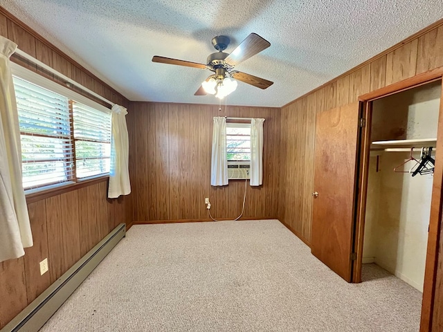 unfurnished bedroom featuring ceiling fan, a textured ceiling, a baseboard heating unit, and wooden walls