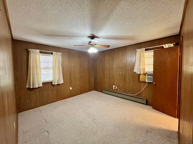 carpeted spare room featuring ceiling fan, a textured ceiling, baseboard heating, and wooden walls