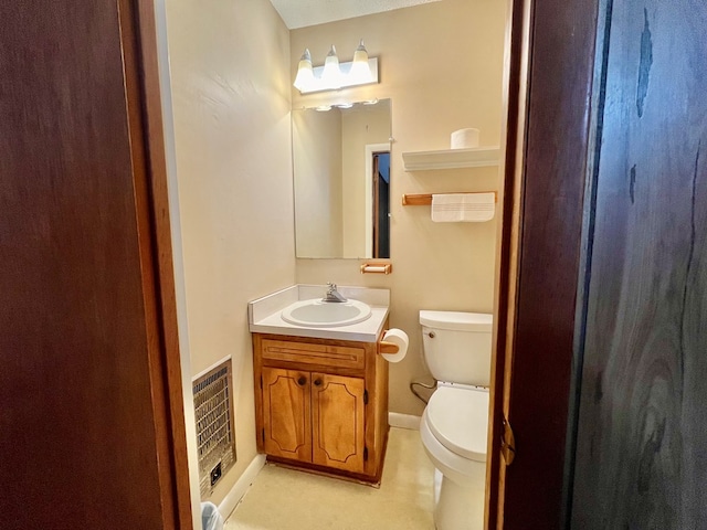 bathroom with toilet, vanity, and heating unit