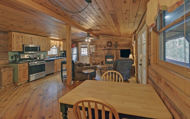 dining area featuring wooden ceiling, light wood-style flooring, wooden walls, and vaulted ceiling