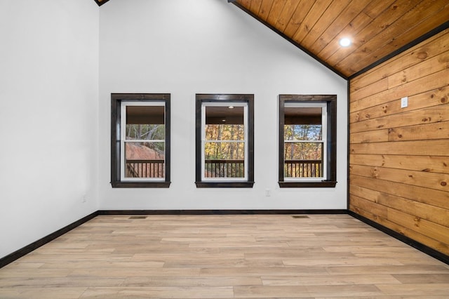 empty room with wood ceiling, wood walls, high vaulted ceiling, and light hardwood / wood-style flooring