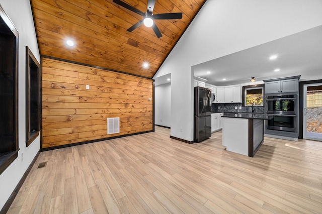 kitchen with wood ceiling, a kitchen island, light hardwood / wood-style flooring, black refrigerator, and wooden walls