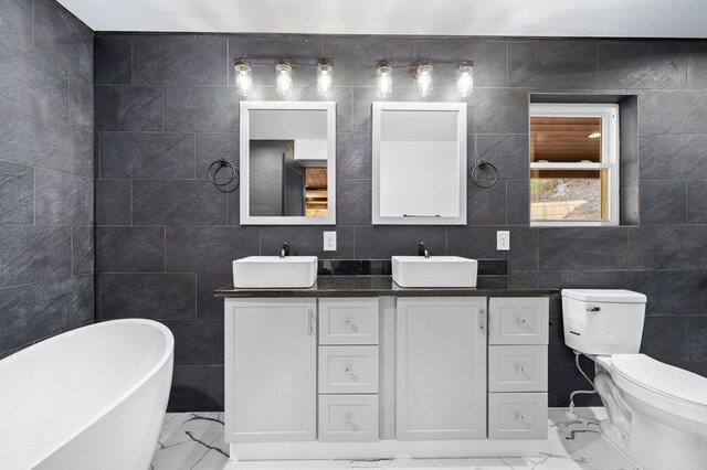 bathroom featuring tile walls, vanity, toilet, and a washtub