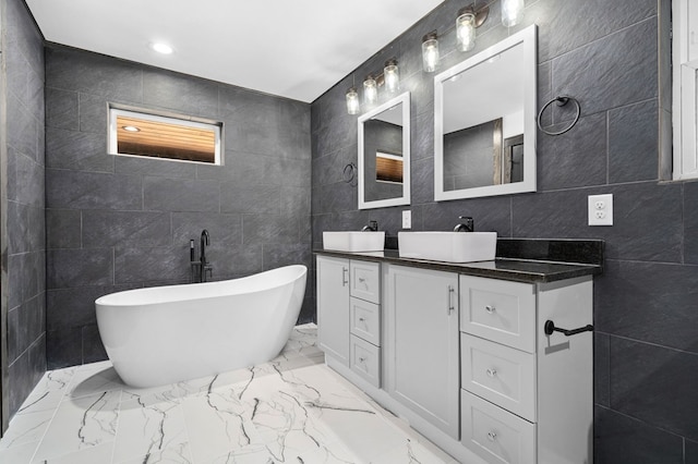 bathroom with vanity, a tub to relax in, and tile walls