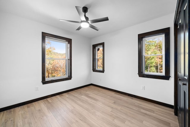 empty room with ceiling fan, a wealth of natural light, and light hardwood / wood-style floors