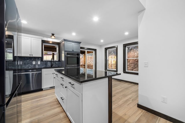 kitchen with a kitchen island, stainless steel appliances, sink, white cabinets, and light hardwood / wood-style floors