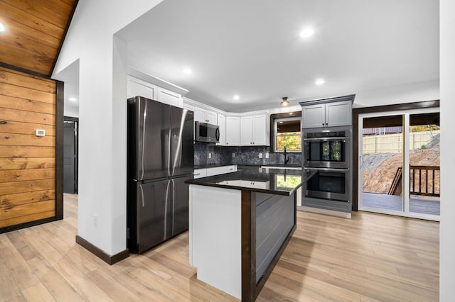 kitchen featuring stainless steel appliances, sink, vaulted ceiling, a center island, and light hardwood / wood-style floors