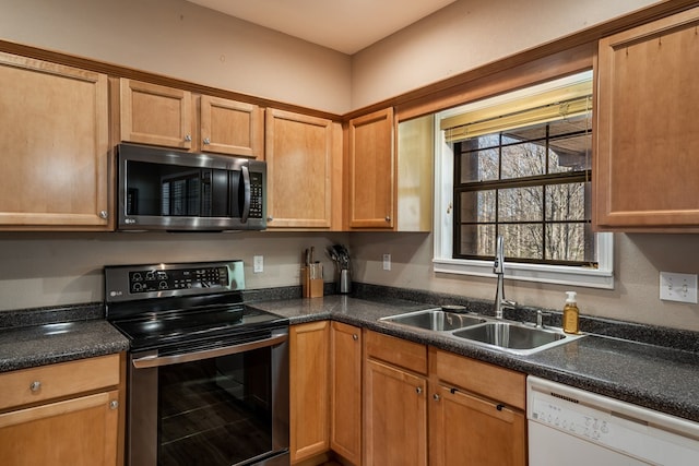 kitchen featuring stainless steel appliances, dark countertops, and a sink