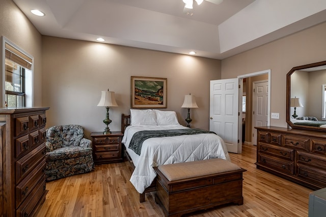 bedroom with light wood finished floors, a raised ceiling, and recessed lighting