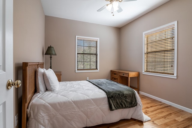 bedroom with light wood finished floors, a ceiling fan, and baseboards