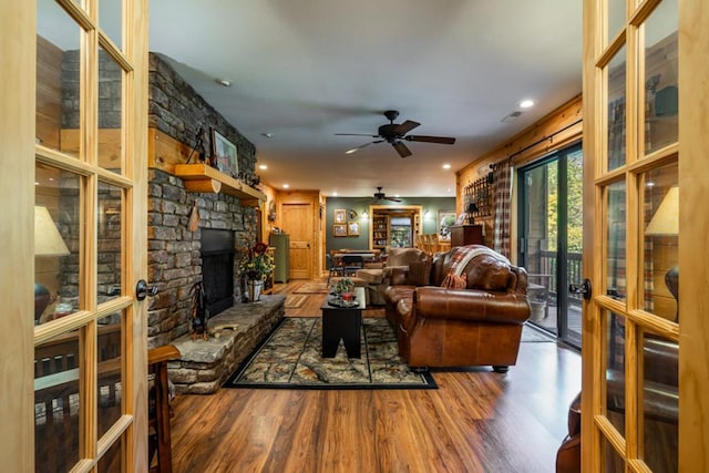 living room featuring french doors, a fireplace, visible vents, ceiling fan, and wood finished floors