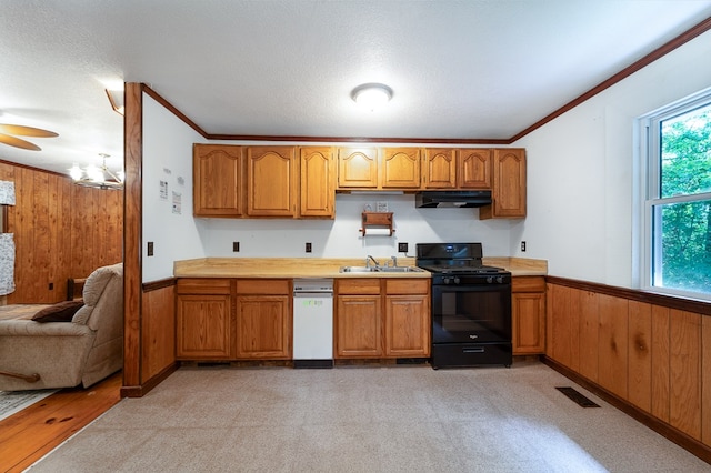 kitchen featuring ornamental molding, light colored carpet, wooden walls, sink, and black gas stove