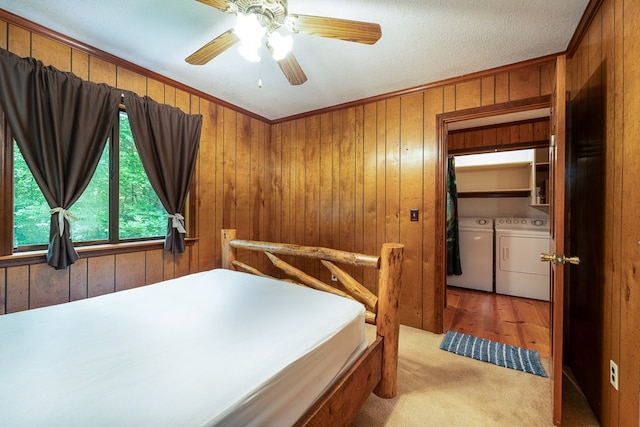 bedroom featuring washer and clothes dryer, ceiling fan, ornamental molding, and wooden walls