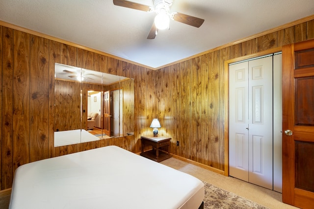 carpeted bedroom featuring a textured ceiling, ceiling fan, and wooden walls