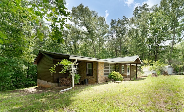 view of front of property with covered porch, a front yard, and a storage unit