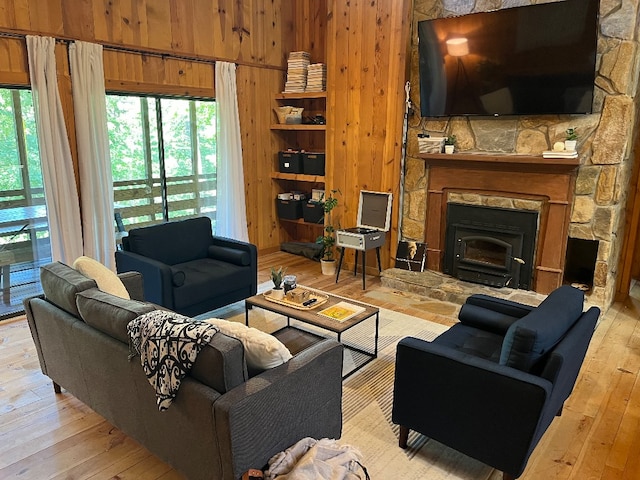 living room featuring a fireplace, light hardwood / wood-style floors, and wooden walls