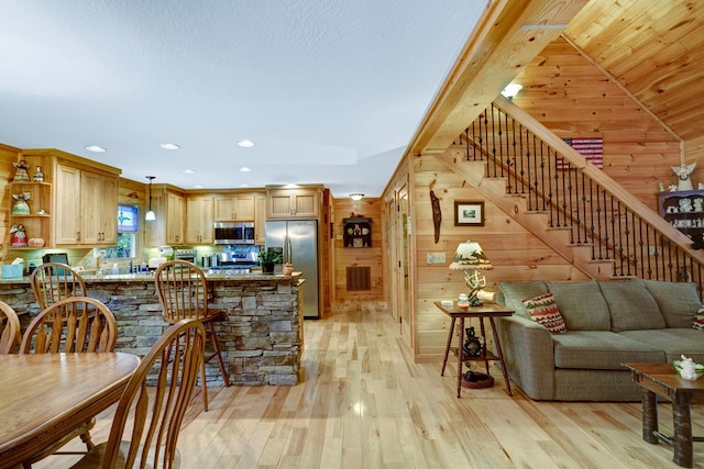 kitchen featuring wood walls, a peninsula, light wood-style floors, stainless steel appliances, and open shelves