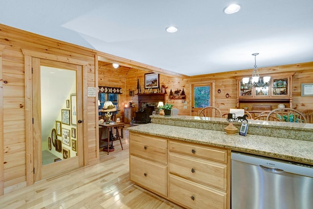 kitchen featuring dishwasher, an inviting chandelier, light wood-style flooring, and wood walls