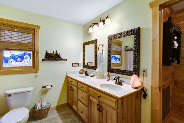 bathroom featuring double vanity, tile patterned flooring, toilet, and a sink