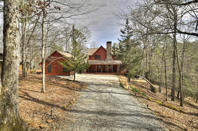 rustic home with gravel driveway and a chimney