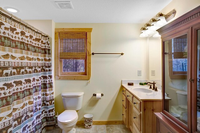 bathroom with visible vents, baseboards, toilet, vanity, and a textured ceiling