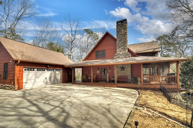 view of front of house featuring an attached garage, a shingled roof, covered porch, a chimney, and driveway