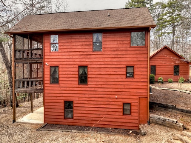 view of side of home featuring a balcony and roof with shingles