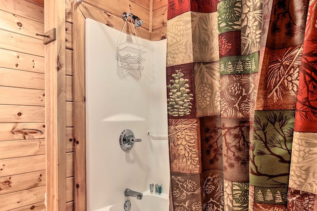 bathroom featuring wooden walls and shower / tub combo with curtain