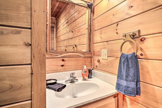 bathroom with vanity and wood walls