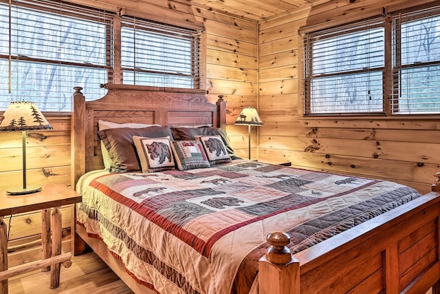 bedroom with light wood-type flooring and wooden walls