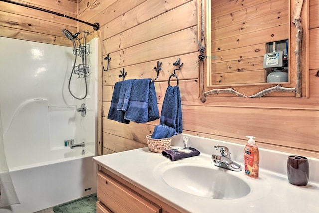 bathroom featuring wood walls, vanity, and bathtub / shower combination